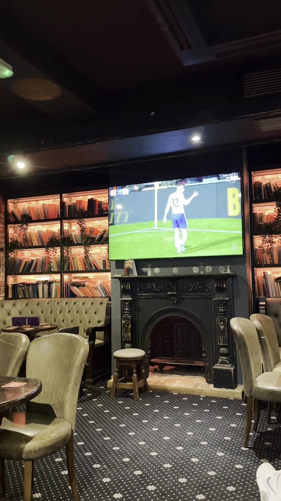 The lounge with a fireplace, bookshelves and a match on the big screen